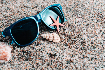 Sunglasses and seashells on the sand. Beach, summer vacation.