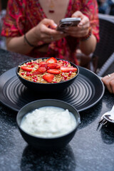 Breakfast granola with yogurt and strawberries on a black plate on a dark background