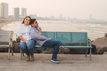 Latin woman living with her only son on Mother's Day, sitting in front of the sea
