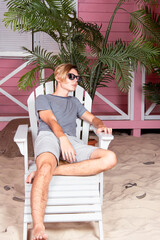 Sea, beach and vacation. A young attractive man is relaxing near his bungalow.