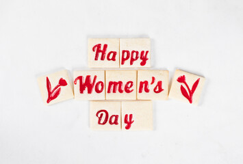 Women's Day. Festive delicate square cookies with marmalade filling of a thematic shape: Happy Women's Day and flowers. White background. Top view