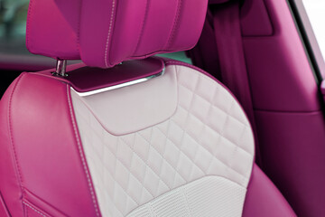 A detailed close up view of a pink perforated stitched leather fabric, showcasing the intricate...