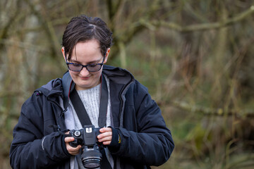 Young photographer teenage girl using DSLR camera outdoors in wood taking photo