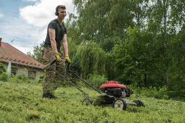 młoda osoba kosząca trawę w ogrodzie