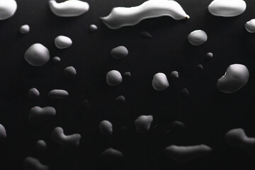gocce di liquido bianco su sfondo nero sfumato
