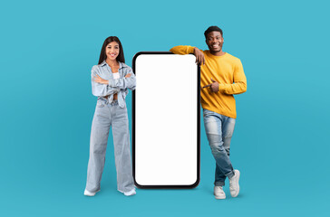 A cheerful multiracial couple presenting a vertically oriented, oversized blank smartphone screen as if showcasing a new app or feature.