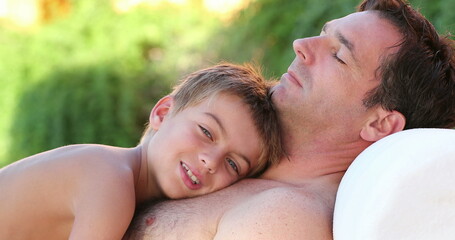 Father and son together small boy laid on dad chest outside