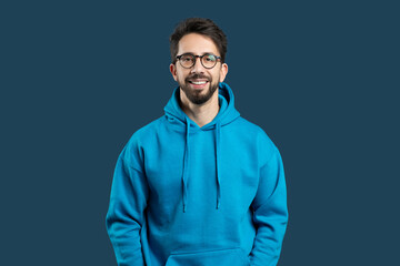 A man with a blue hoodie and glasses is standing in the image. He appears to be looking straight...