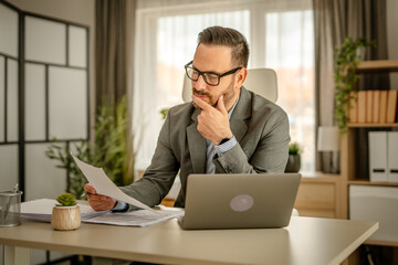 One men working in the office using technology and looking at paper