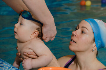 Baby in goggles for swimming pool. Child eyes protection from water. Healthy family, early development