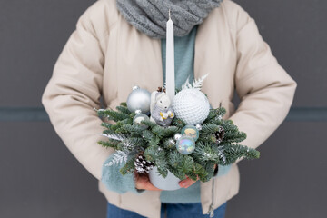 Person Holding Christmas Arrangement, holiday decorations and colors.