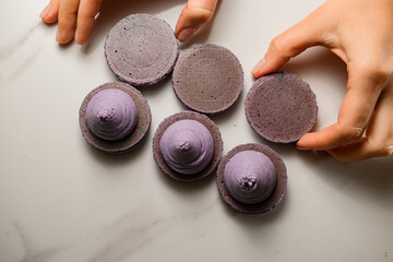 Delicious lilac macaroons on a marble table and woman's hands