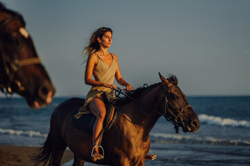 Beautiful girl model on horseback on the sandy coastline during a summer