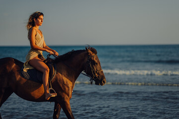 Side view of a woman galloping on a horse on a beach