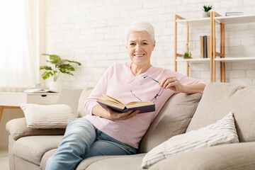 Learning foreign languages. Cheerful senior woman reading educational book at home
