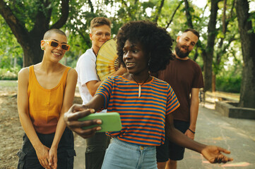 Interracial college students taking selfies in campus on a break.