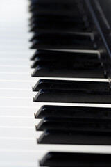 A piano, focusing on its black and white keys. The keys are clean, reflect light. The perspective...