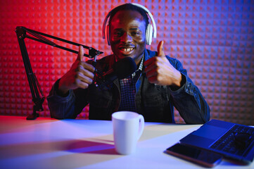african american vlogger using smartphone to film podcast in studio. blogger with mobile phone,...