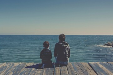 A father and son are sitting together on top of a wooden pier, looking out at the ocean, A father and son sitting on a pier, looking out at the ocean