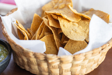 container with nacho chips type corn tortilla chips, on wooden table