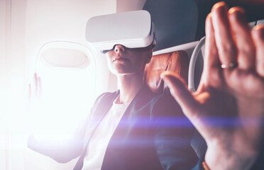 Businesswoman exploring virtual reality for controlling successful business solutions and development of a work plan.Contemporary advanced technology and innovation. Female wear VR gadget in airplane