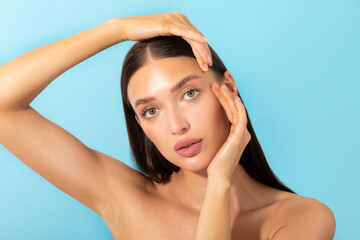 Skincare and beauty. Young lady touching shiny healthy skin, nourished face after facial serum and moisturizer, blue background