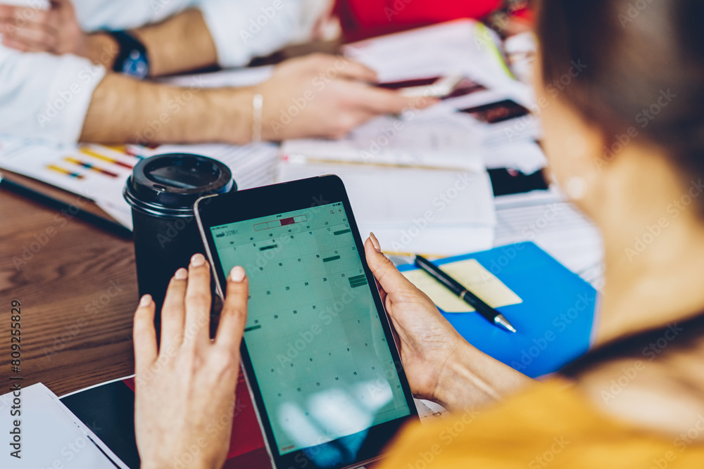 Poster cropped back view of young woman holding modern touch pad device in hands and searching app on inter