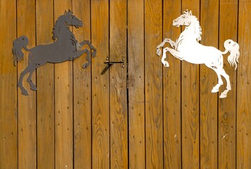 Dwa konie - czarny i biały na bramie stajni