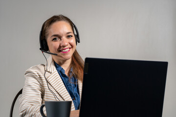 Mujer asistente en una tele llamada, contenta y mirando a cámara. Concepto de mesa de ayuda y asistencia virtual