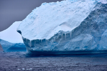 Blue iceberg with large ice cycles hanging down in Antarctica.