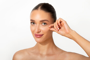 Young European woman touching her cheek and smiling at camera over white background. Cheek filler...