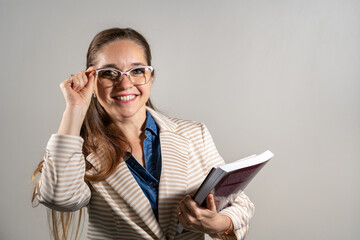 Mujer universitaria sosteniendo sus notas y libros mientras sonrie a cámara