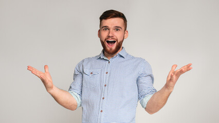 Hey you. Young exited man raising hands and happy screaming on studio background, panorama