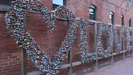 Naklejka premium Love letters made of locks at the distillery district in the city of Toronto Old Town is a great photo Opportunity in the city - TORONTO, CANADA - APRIL 15, 2024