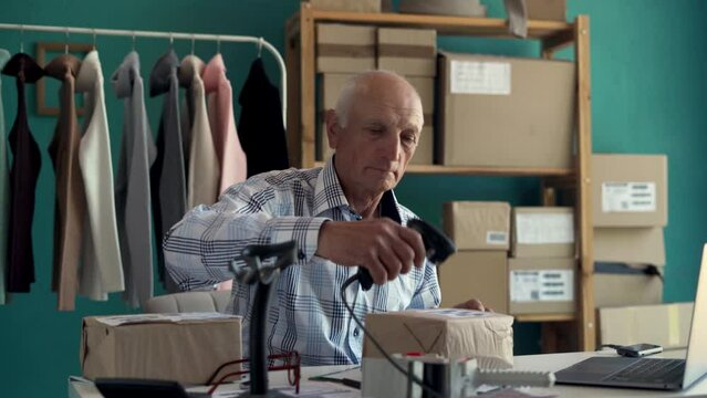 Male seller online store worker using scanner for scanning parcel bar code, post shipping box online shop order in delivery service.