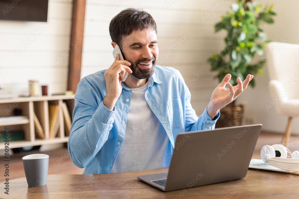 Poster A man is multitasking as he talks on a cell phone and works on a laptop simultaneously. He appears focused and engaged in his tasks, showing efficient use of technology in a modern workspace.