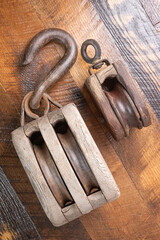Two antique block and tackle on wooden background.