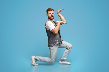 Funny millennial guy dancing in egypt style on blue background, studio, copy space