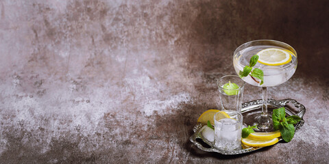 Various glasses on silver tray filled with cold drinks with ice, lemon and mint