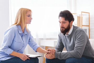 A man sitting down appears to be sharing personal concerns with a woman, possibly a counselor or...