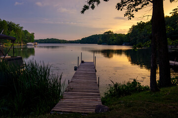 Looking down a pier, onto a calm Wisconsin lake in the evening as the sun goes down. © Jennifer