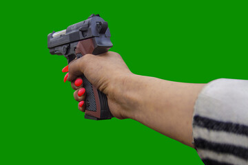 The hand of a man with red nails clutches a black pistol, and all this on a bright green background. The scene suggests violence and danger.