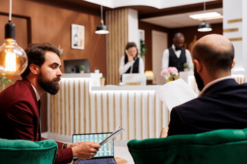Business travellers conducting global scale project, meeting in hotel lounge area while they travel...