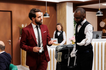 Bellboy taking guest to his hotel room, providing excellent luxury service for businessman with...