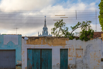 Rustic wall facade with wooden doors and Christian church tower in the background