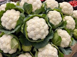 A vibrant display of fresh organic cauliflower at a local farmer's market, showcasing the natural beauty of the vegetable and the vibrant atmosphere of the market.
