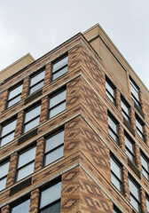 tall apartment building detail with colorful bricks, windows reflecting cloudy sky (housing real estate flats new jersey waterfront)