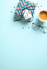 Happy Fathers Day gift box, coffee cup, glasses on pastel blue background. Flat lay, top view, copy space.