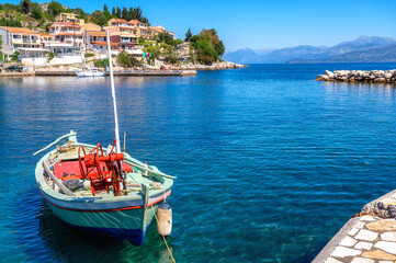 Wunderschöne Hafenstadt Kassiopi auf Korfu mit Fischerboot im türkisblauen Wasser des Mittelmeers