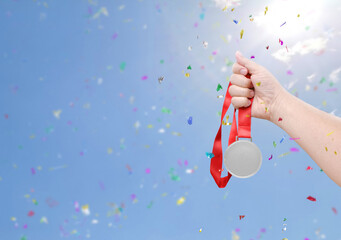 Holding a silver medal coin celebrating success sky background